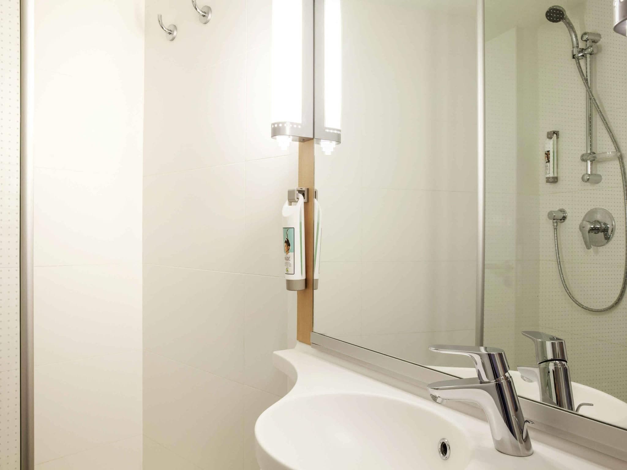 Un baño moderno con un lavamanos blanco, accesorios de cromo y cabina de ducha con paredes de vidrio.