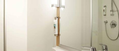 Un baño moderno con un lavamanos blanco, accesorios de cromo y cabina de ducha con paredes de vidrio.