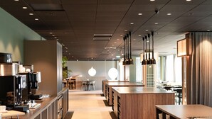 A modern restaurant interior with a long counter, hanging pendant lights, and a central seating area.