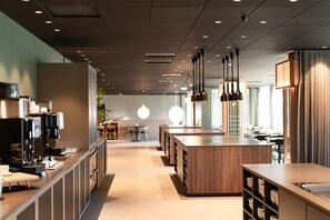 A modern restaurant interior with a long counter, hanging pendant lights, and a central seating area.