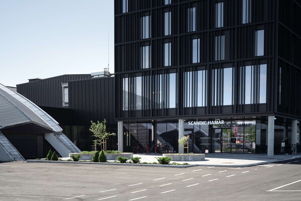 A modern building with a glass facade and a sign reading "SCANDIC HAMAR".