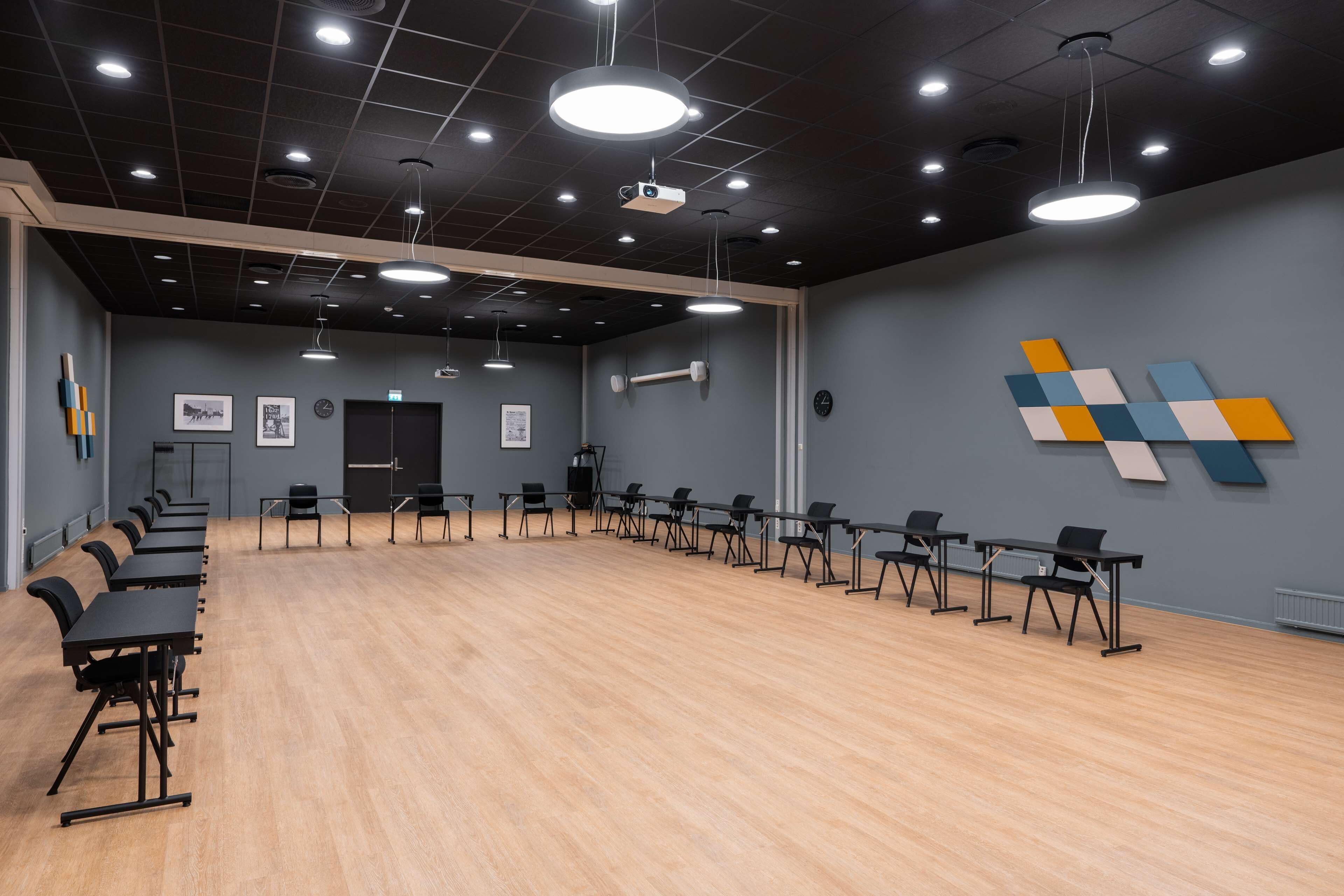 A conference room with a long table and chairs, a projector, and a clock on the wall.