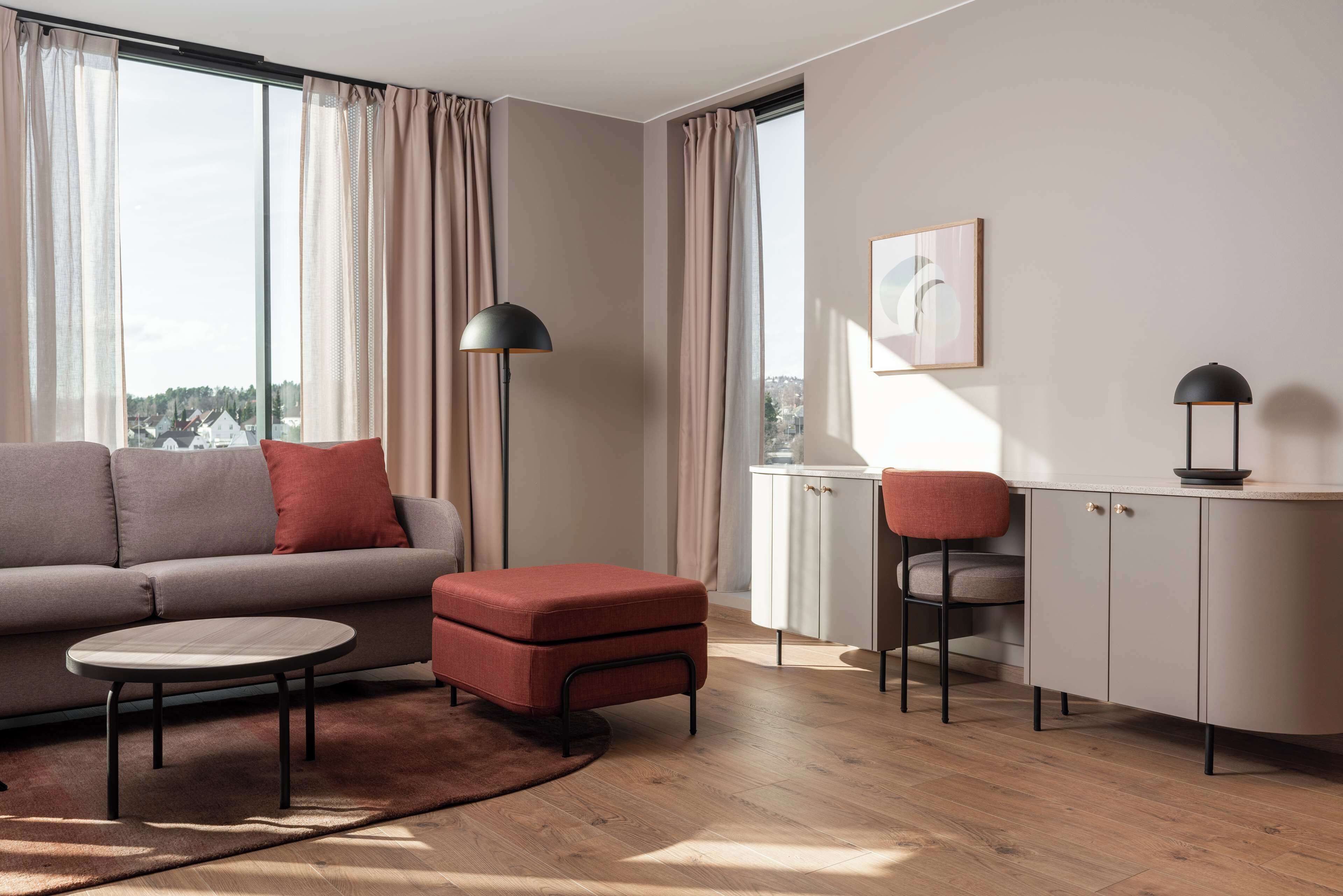 A modern living room with a sofa, ottoman, round coffee table, and a cabinet with a chair.