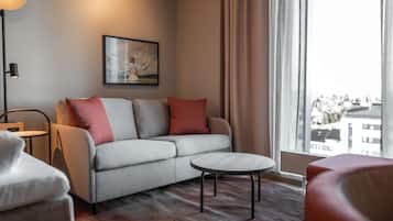 A modern living room with a grey sofa, red and grey cushions, a round coffee table, and a floor lamp.