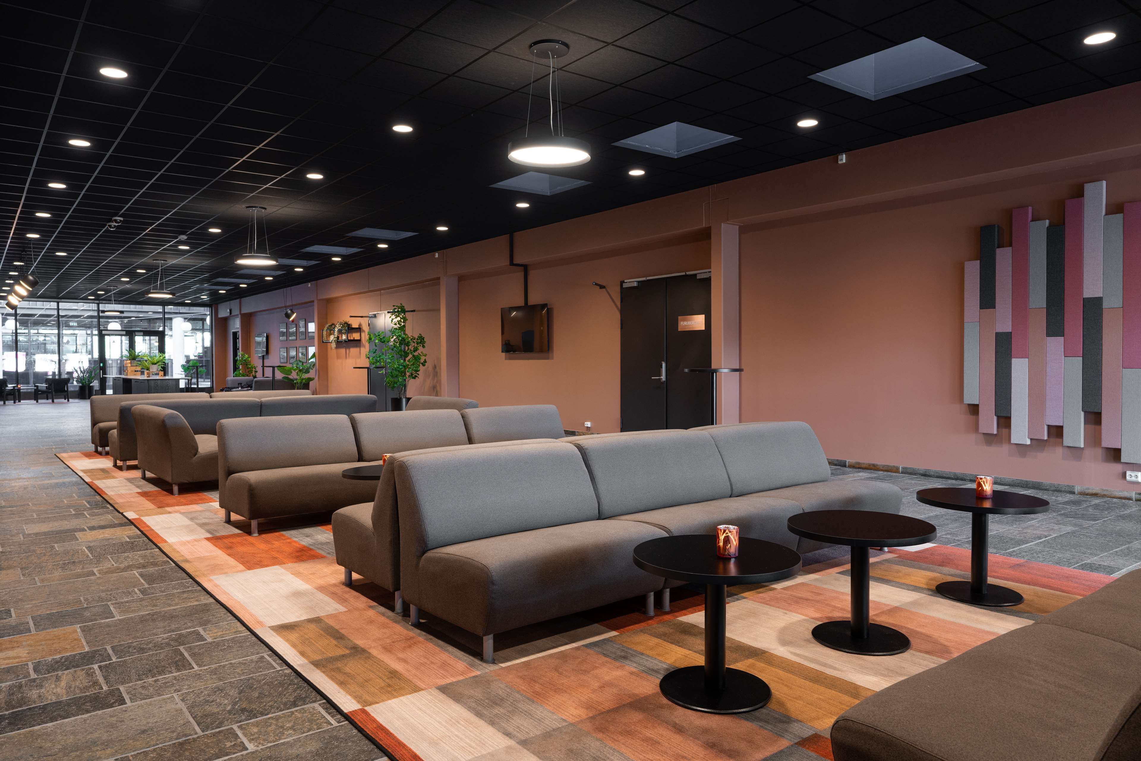 A modern lounge area with sofas, tables, and a patterned carpet.