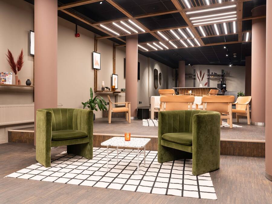 A modern lobby with green armchairs, a coffee table, and a reception desk.