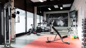 A gym with exercise equipment, a red mat, and a large window.