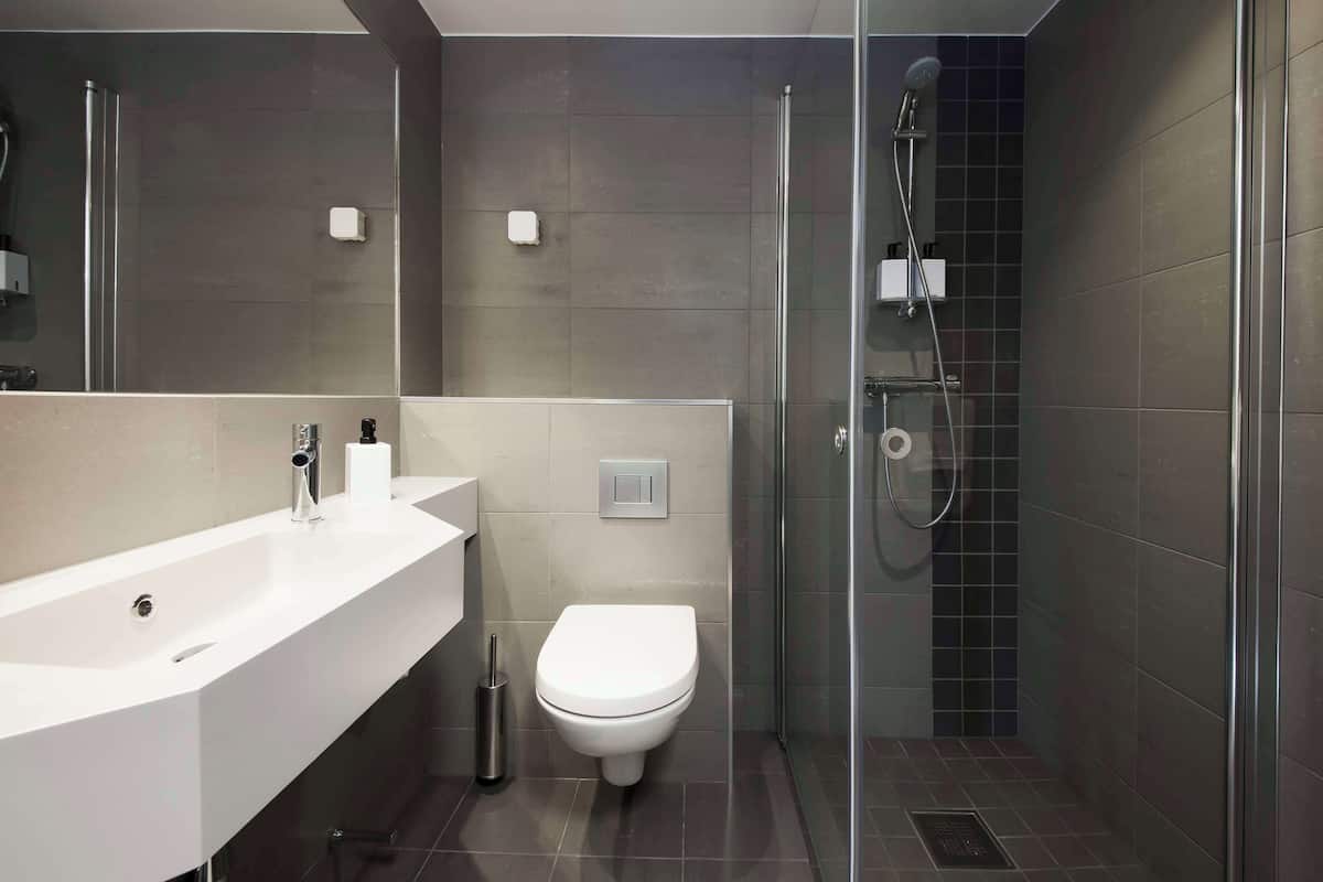 A modern bathroom with a white sink, toilet, and glass-enclosed shower.