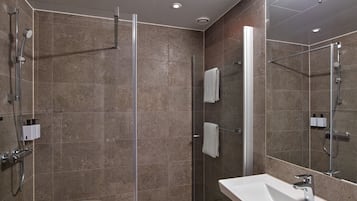 Un baño moderno con ducha envuelta en vidrio, un lavamanos blanco y un espejo grande.