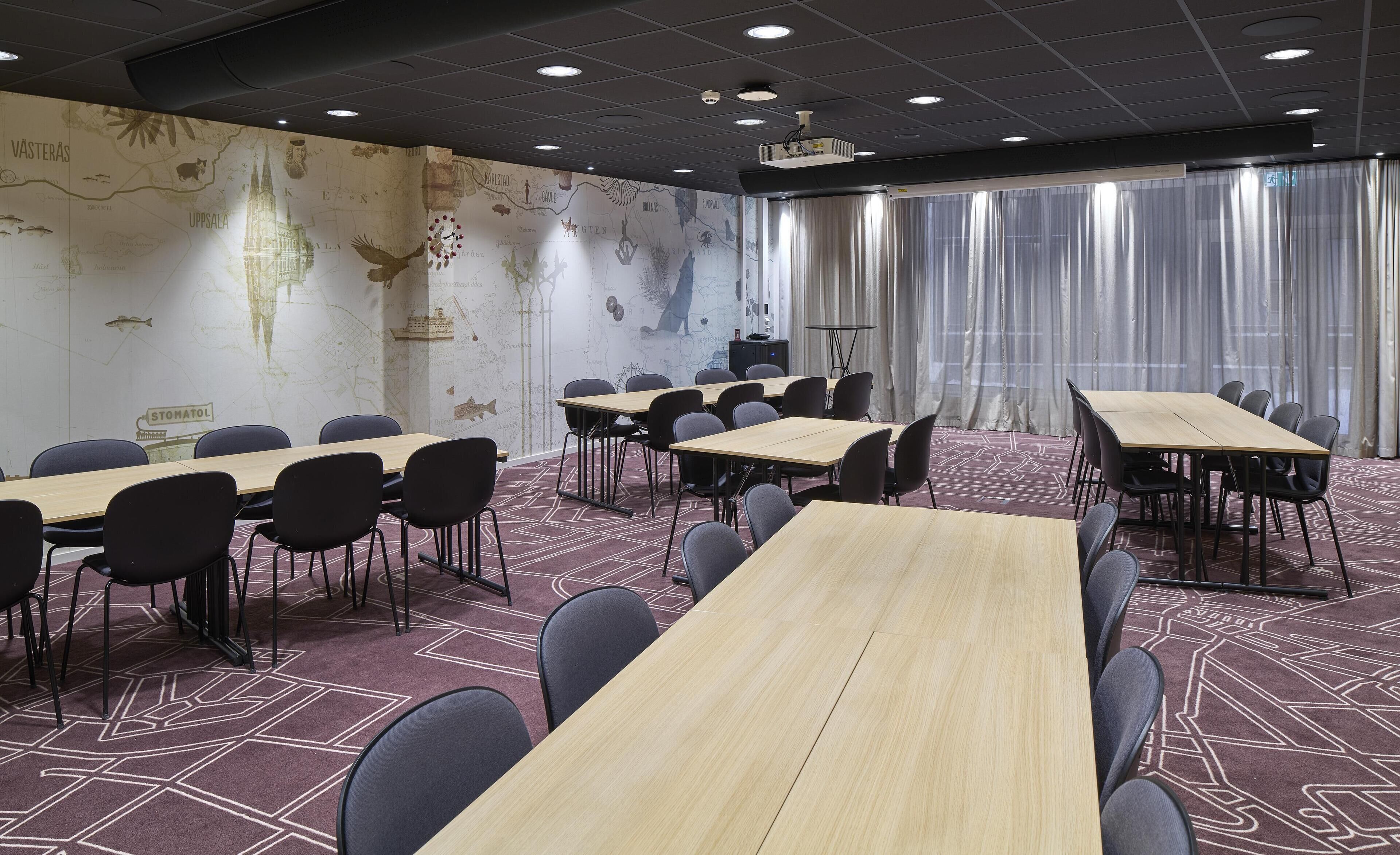 A conference room with long tables and chairs, a projector, and a map on the wall.