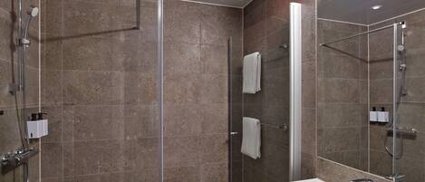 A modern bathroom with a glass-enclosed shower, a white sink, and a large mirror.