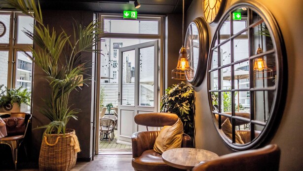 A cozy interior with leather chairs, a wicker basket, and a view through a window.