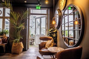 A cozy interior with leather chairs, a wicker basket, and a view through a window. - Scandic Webers (Copenhagen)