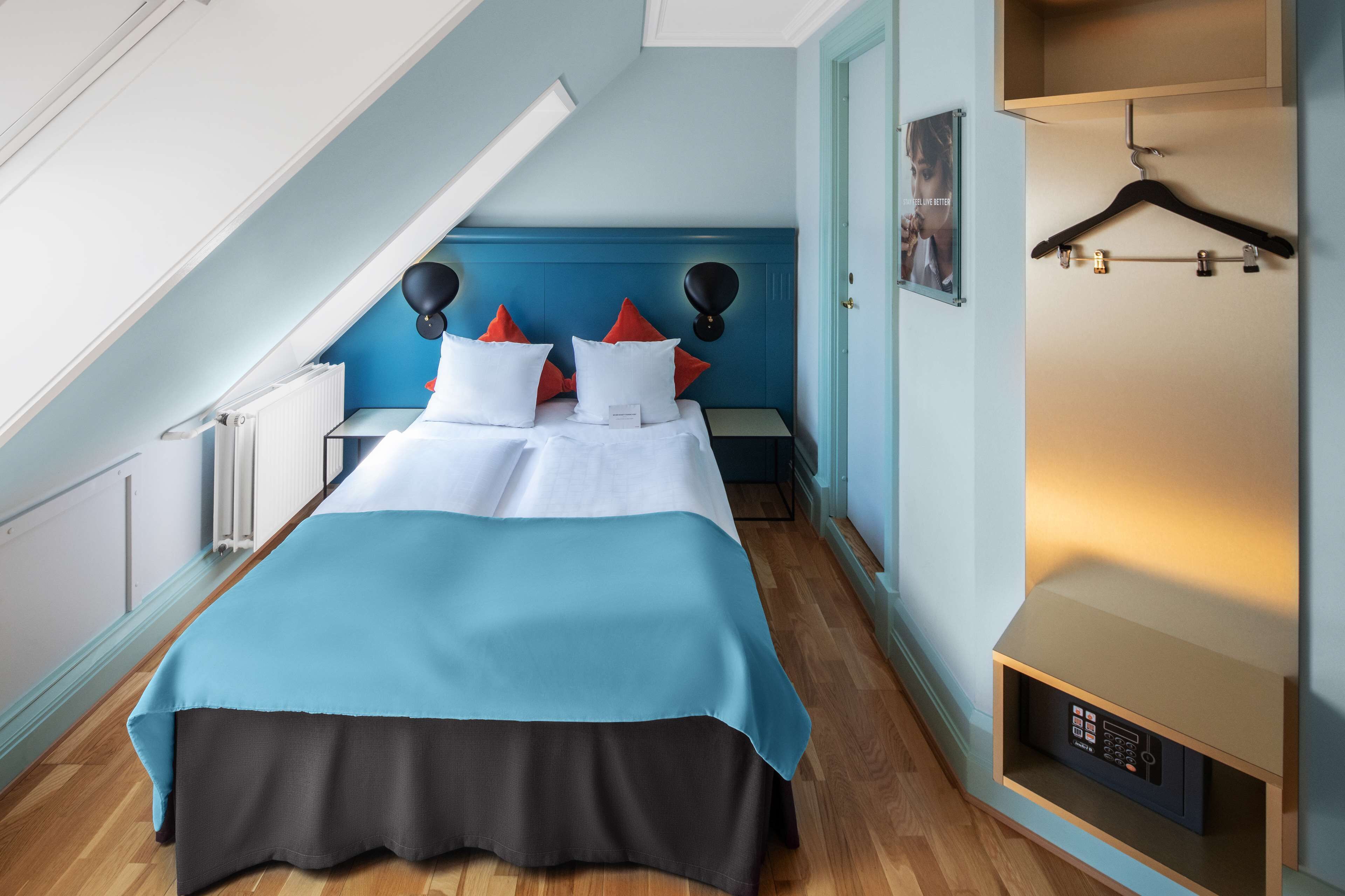 Un dormitorio con una cama, una mesita de noche, un aparador y una lámpara colgante.