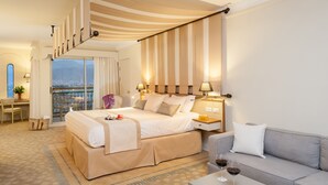 Una habitación de hotel con una cama grande, un sofá, un escritorio y un balcón con vista a la ciudad.