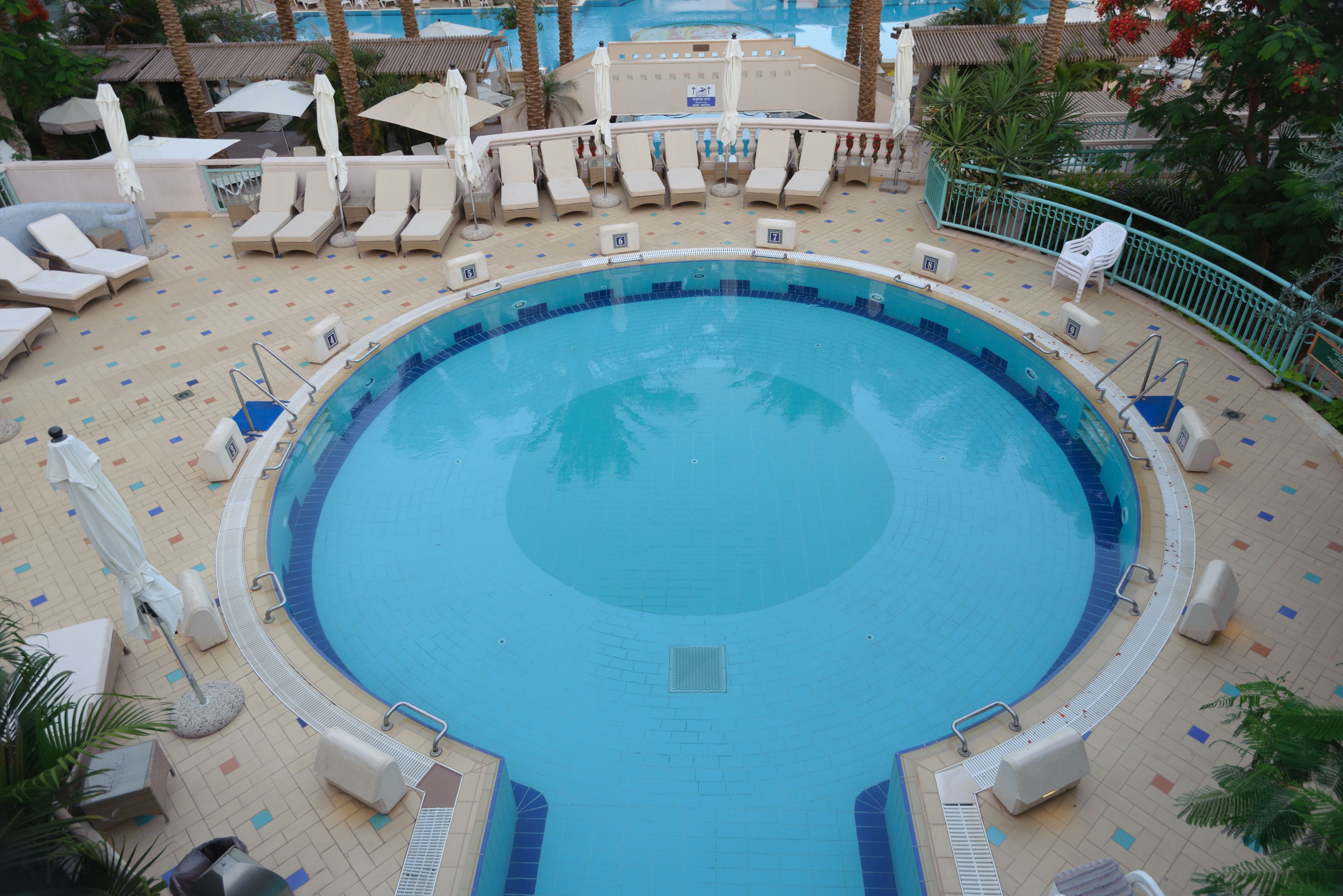 A large, circular pool with lounge chairs and umbrellas around it.