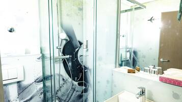 Ein modernes Badezimmer mit einer Duschkabine aus Glas, einem weißen Waschbecken und einem Spiegel darüber.