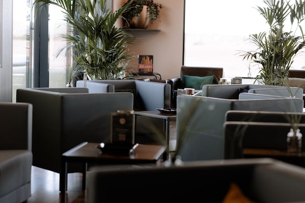 A modern interior with seating arrangements, potted plants, and a visible window. - Sombea Donaueschingen (Donaueschingen)