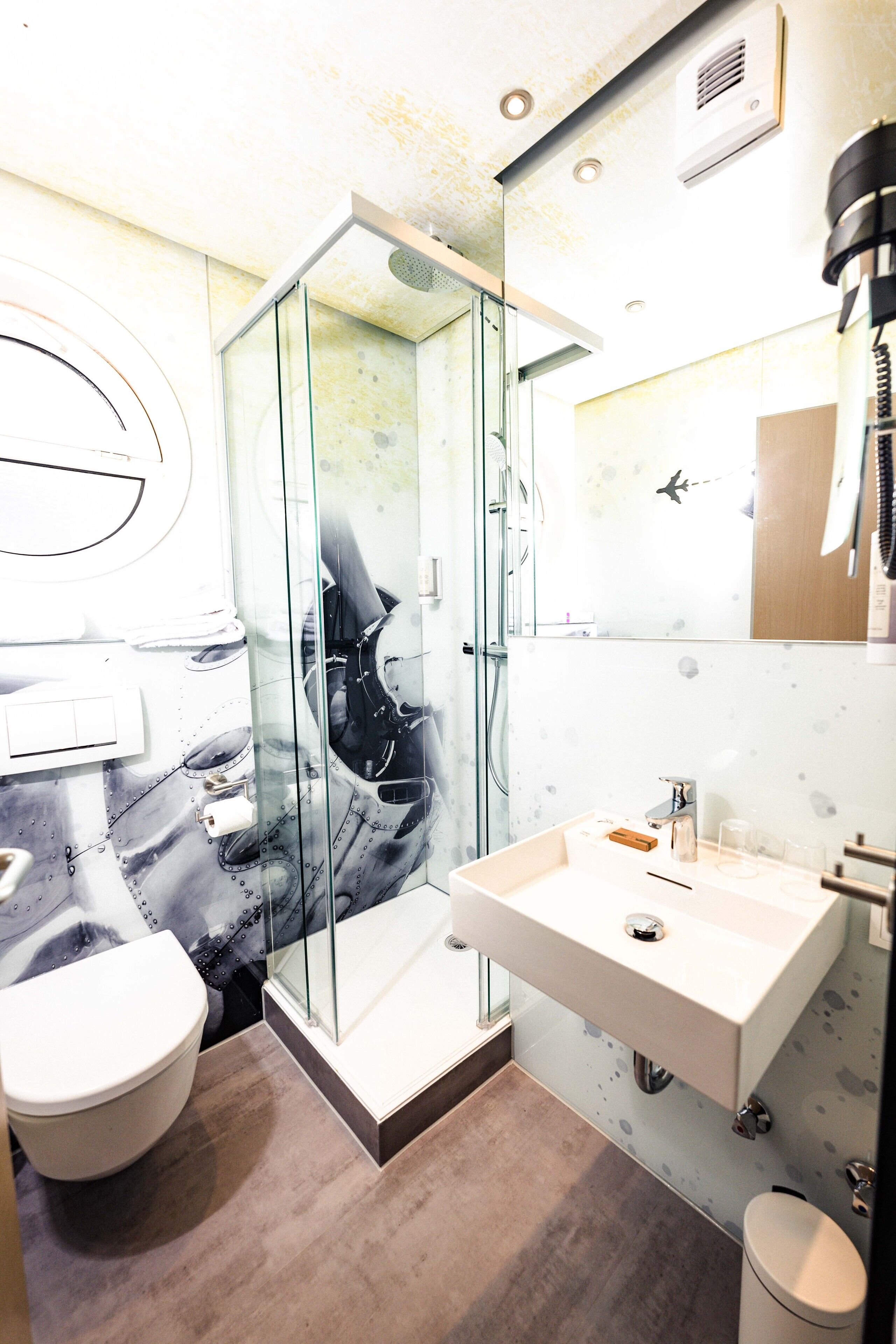 A modern bathroom with a glass shower enclosure, a white sink, and a toilet.