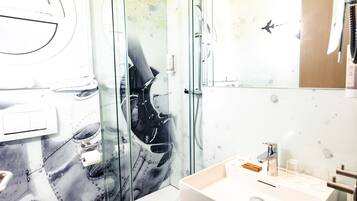 A modern bathroom with a glass shower enclosure, a white sink, and a toilet.