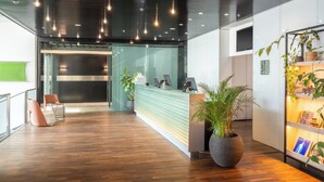Een moderne receptie met een houten vloer, een receptiebalie en verschillende plantenpotten.