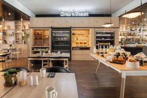 Un café moderno con un letrero que dice 'Grab a Snack', una zona de bar con botellas y una mesa de buffet con diferentes opciones de comida.