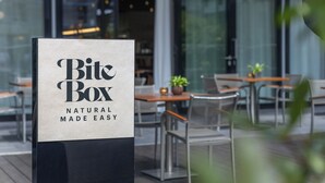 A sign for 'BiteBox' with a modern outdoor seating area in the background.