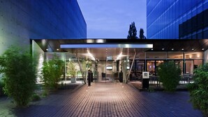 Een moderne gevel met glazen deuren, een overdekte doorgang en een terras.