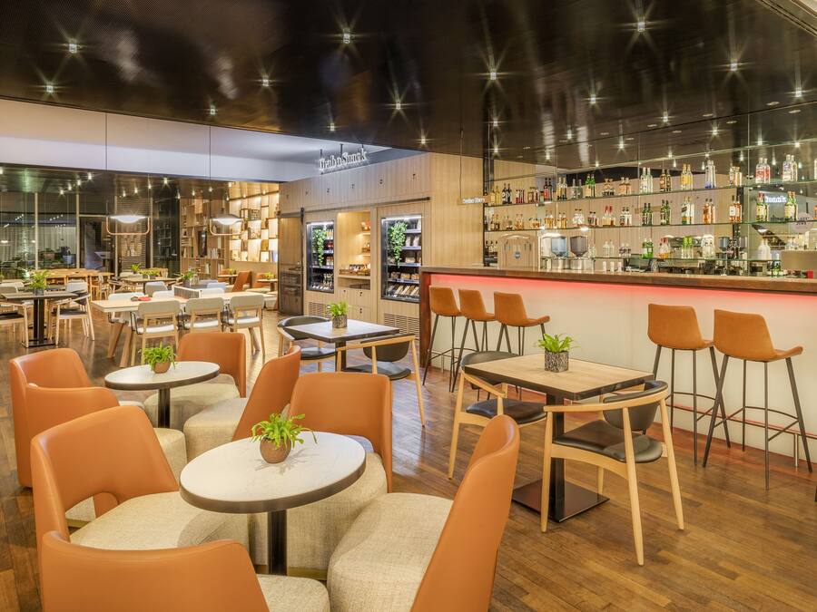 A modern bar area with a variety of seating options including round tables and bar stools.