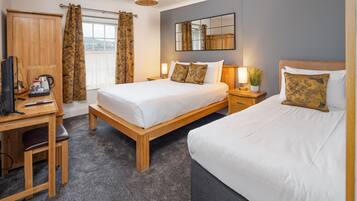 Habitación de hotel con un escritorio de madera, dos camas, un espejo grande y vista a la ciudad.