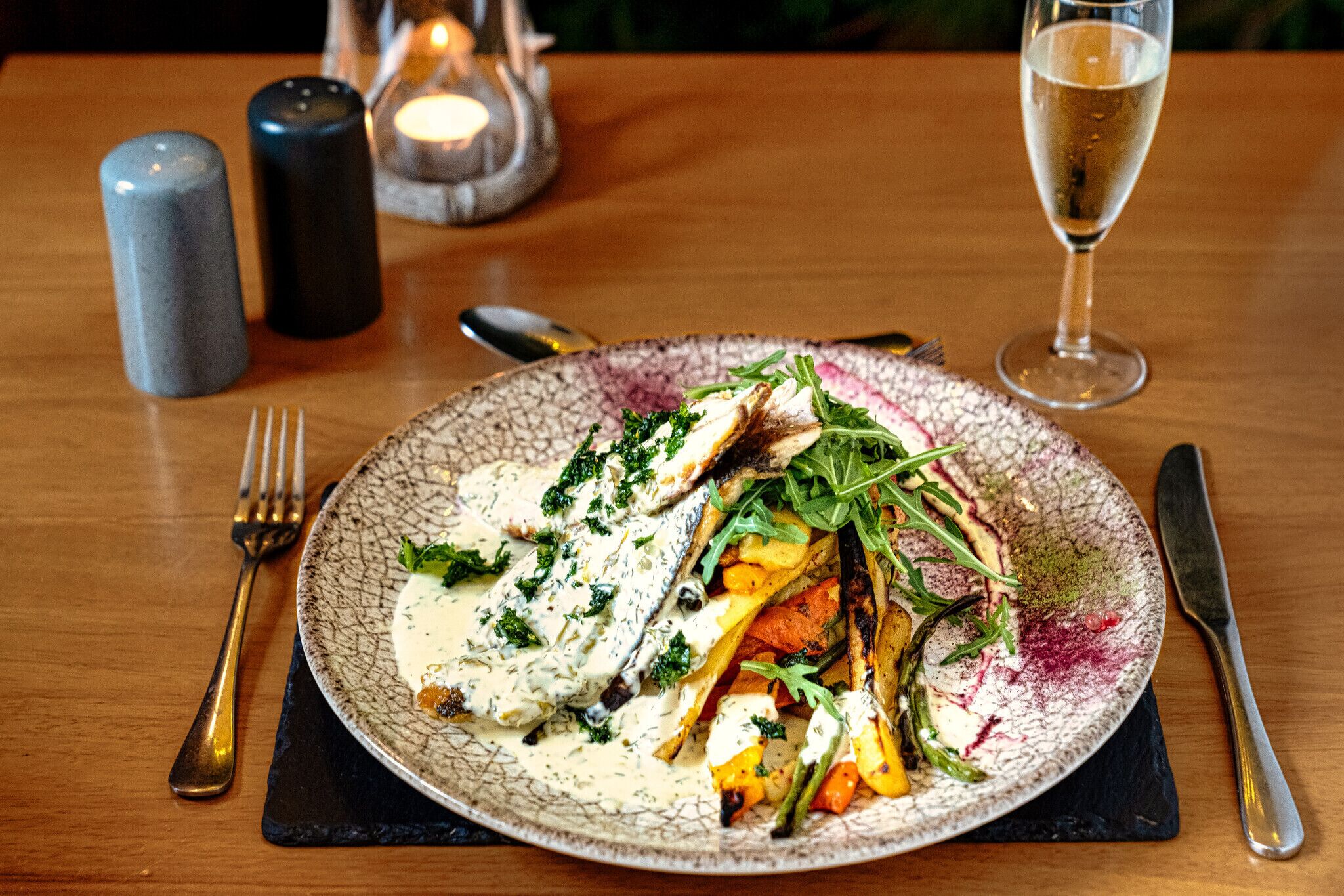 A plate of food with a fork and knife on a wooden table.