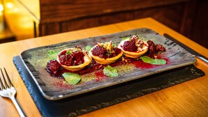 A dessert plate with three halves of a tart, garnished with berries and mint leaves, on a slate serving board. - Boars Head Hotel (Carmarthen)