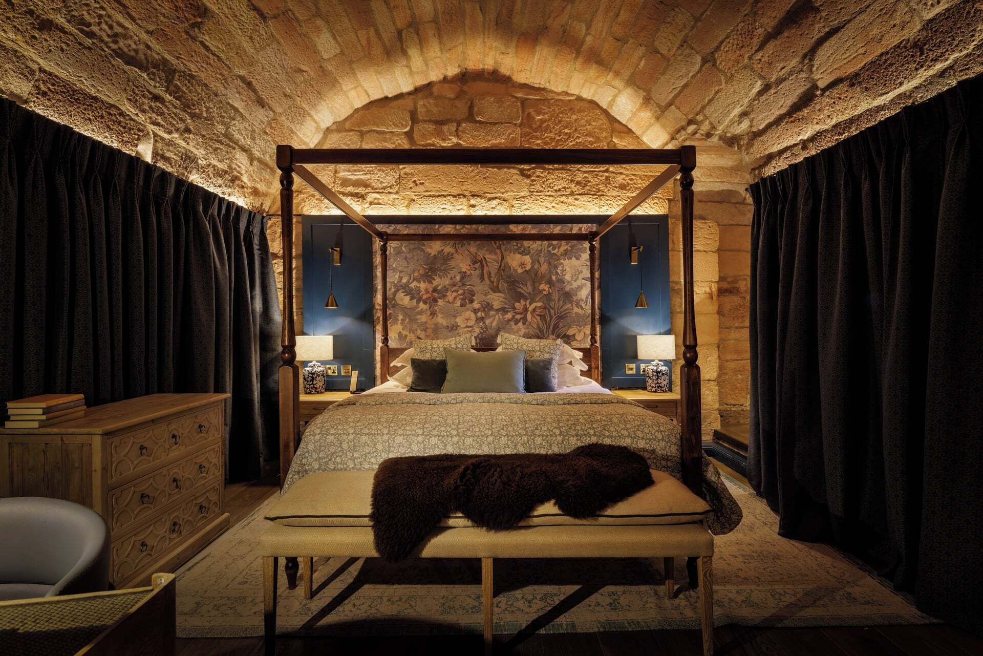 Una cama con dosel en una habitación con paredes de piedra y techo de madera.