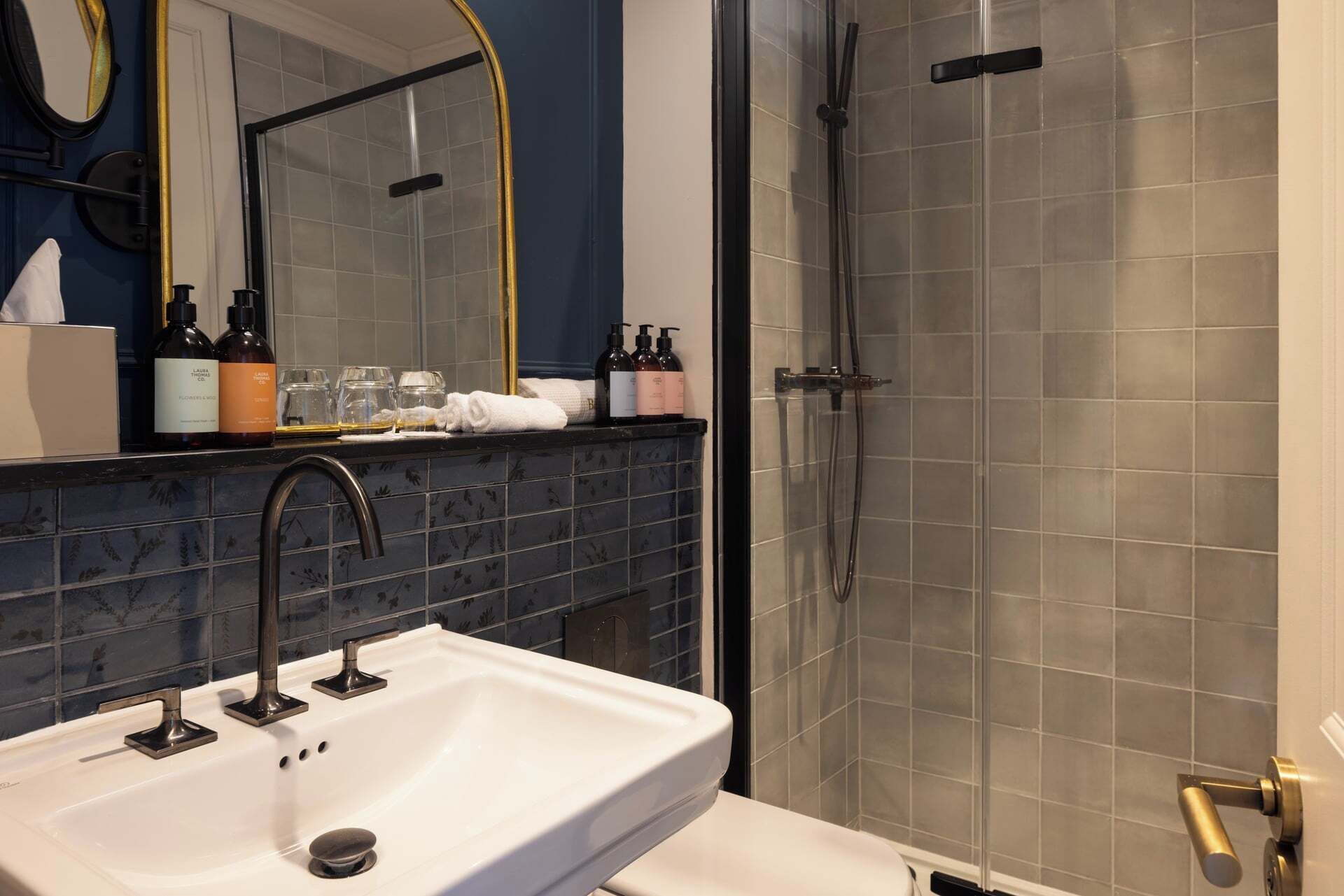 Un baño con un lavabo blanco, un espejo y una ducha con puerta de cristal.