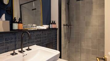 Un baño con un lavabo blanco, un espejo y una ducha con puerta de cristal.