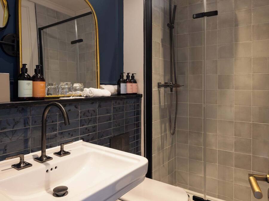 Un baño con un lavabo blanco, un espejo y una ducha con puerta de cristal.