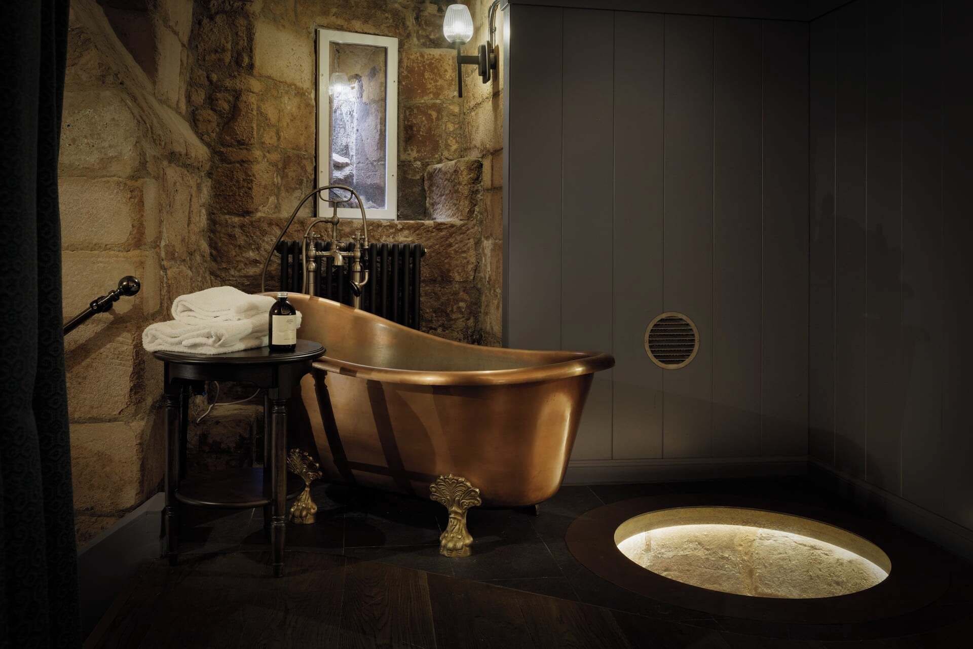 A bathroom with a vintage bathtub, a towel, a bottle, and a radiator.