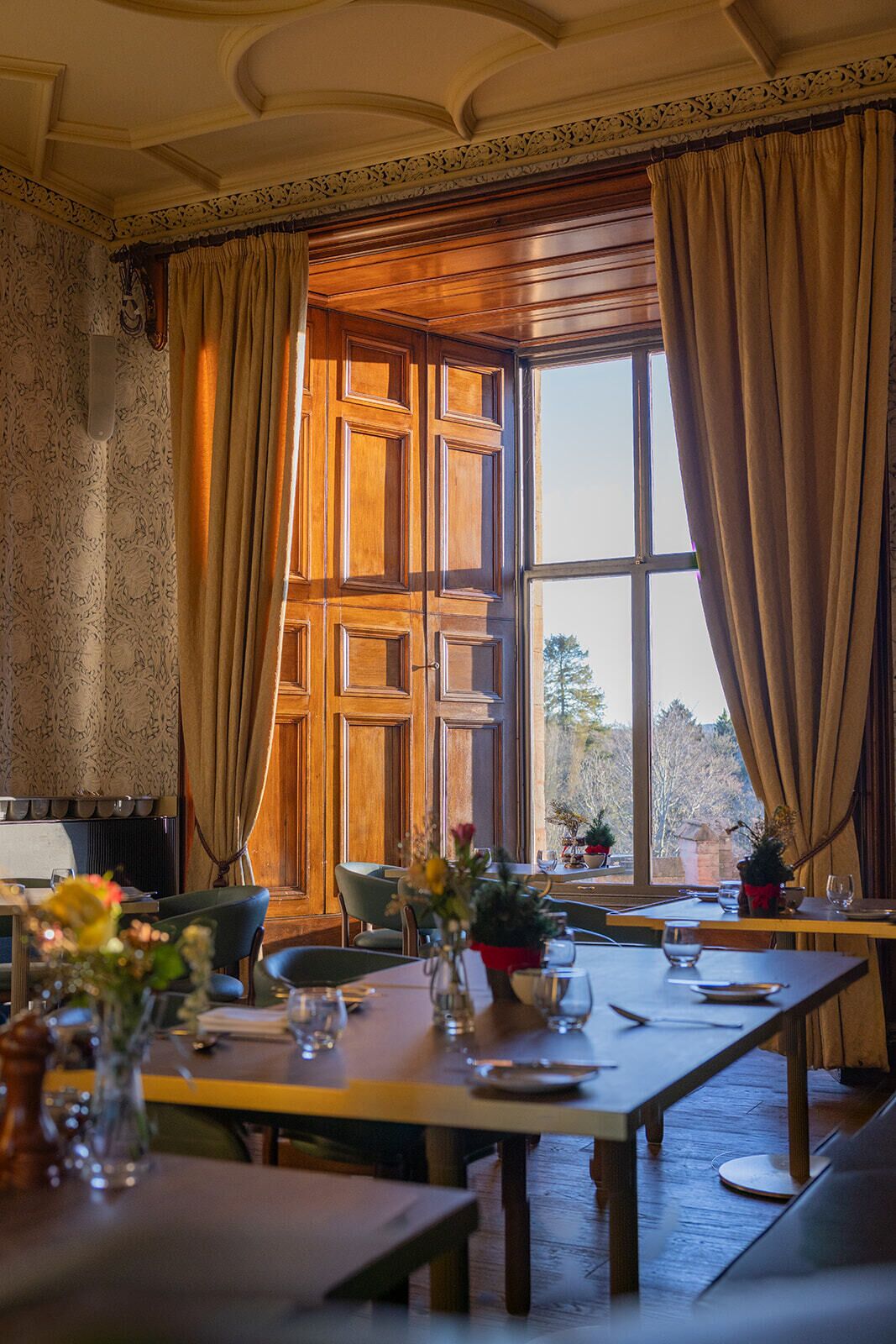 A dining area with a large window, wooden paneling, and a table set for two.