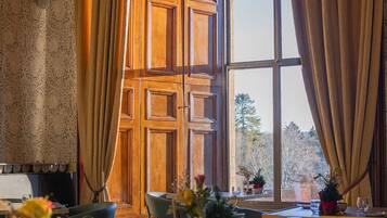 A dining area with a large window, wooden paneling, and a table set for two.