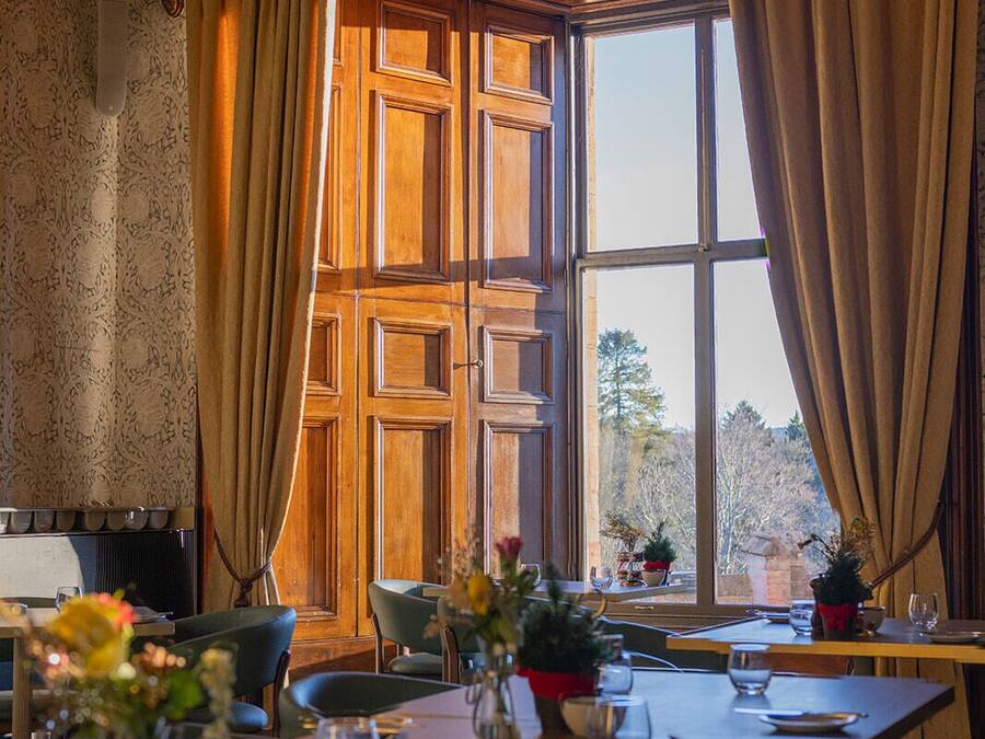A dining area with a large window, wooden paneling, and a table set for two.