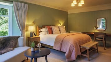 Une chambre d’hôtel avec un lit, une table de chevet, une lampe, une chaise et une petite table sur laquelle se trouve une plante.
