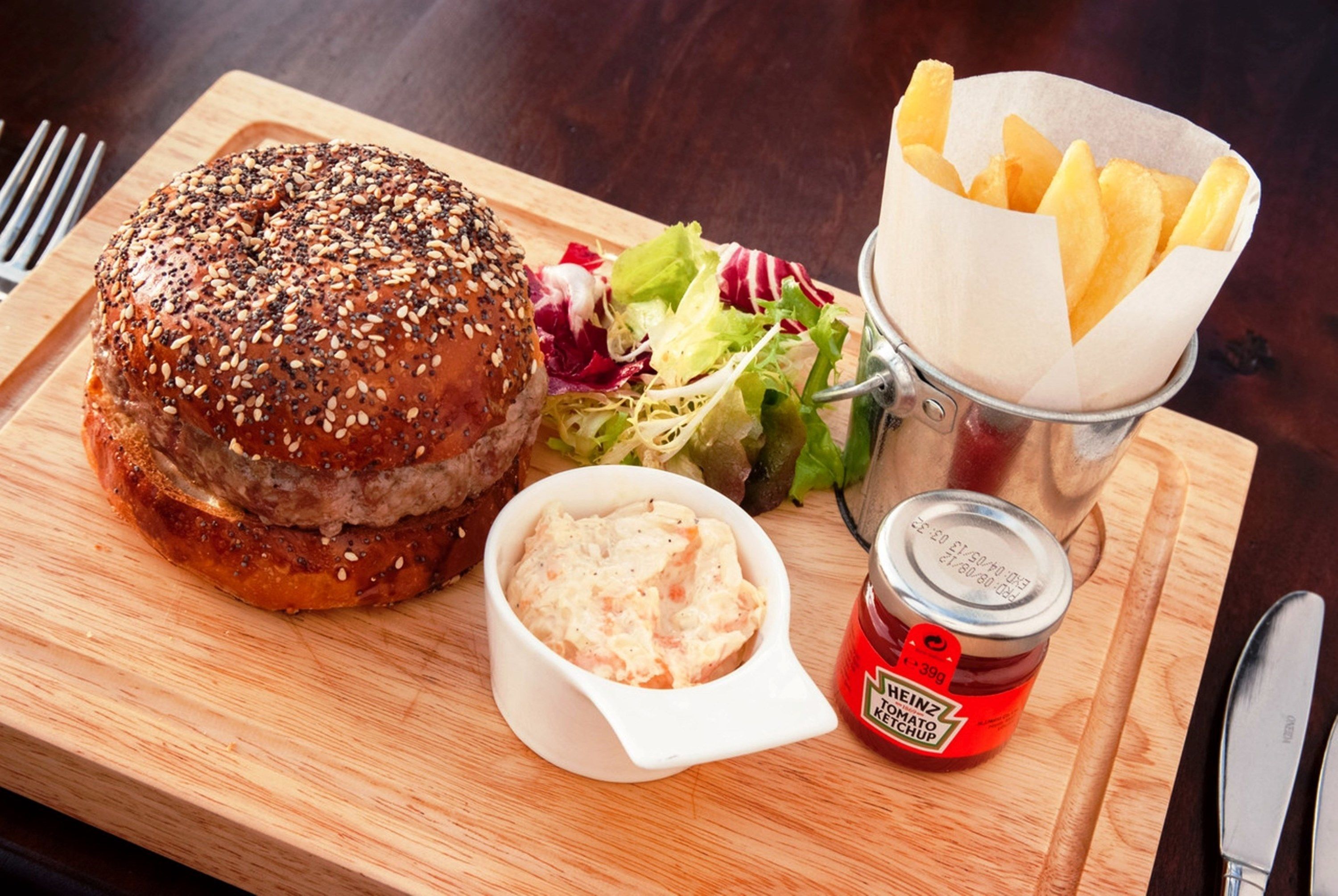 A meal with a burger, fries, salad, and a small container of ketchup.