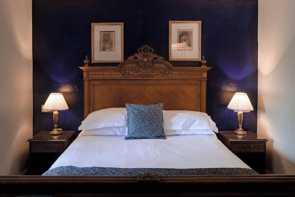 A bed with a wooden headboard, two bedside lamps, and two framed pictures above the bed.