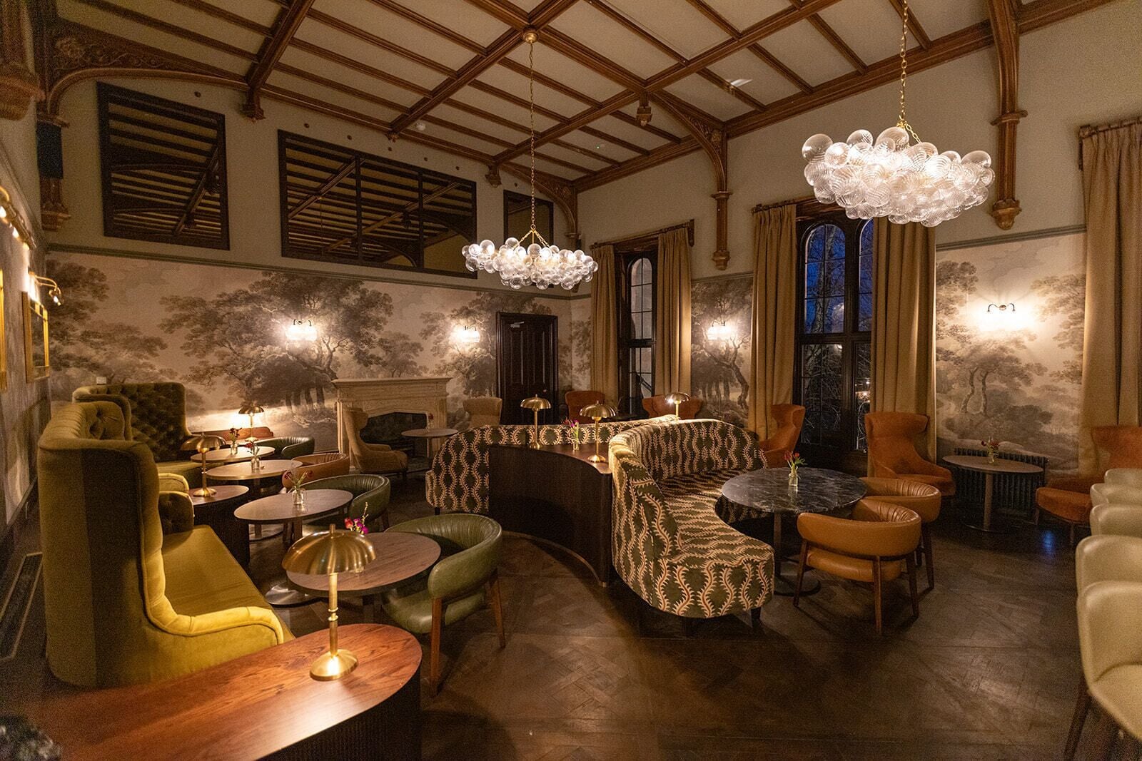 A room with a fireplace, multiple seating areas, and a chandelier.
