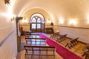A church interior with wooden pews, a red carpet, and a stained glass window. - Dalhousie Castle (Bonnyrigg)
