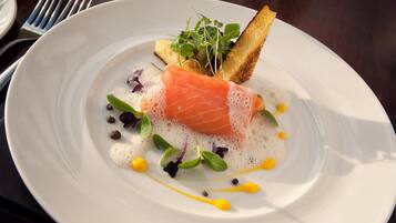 Un plato de comida con salmón, espuma y guarniciones.