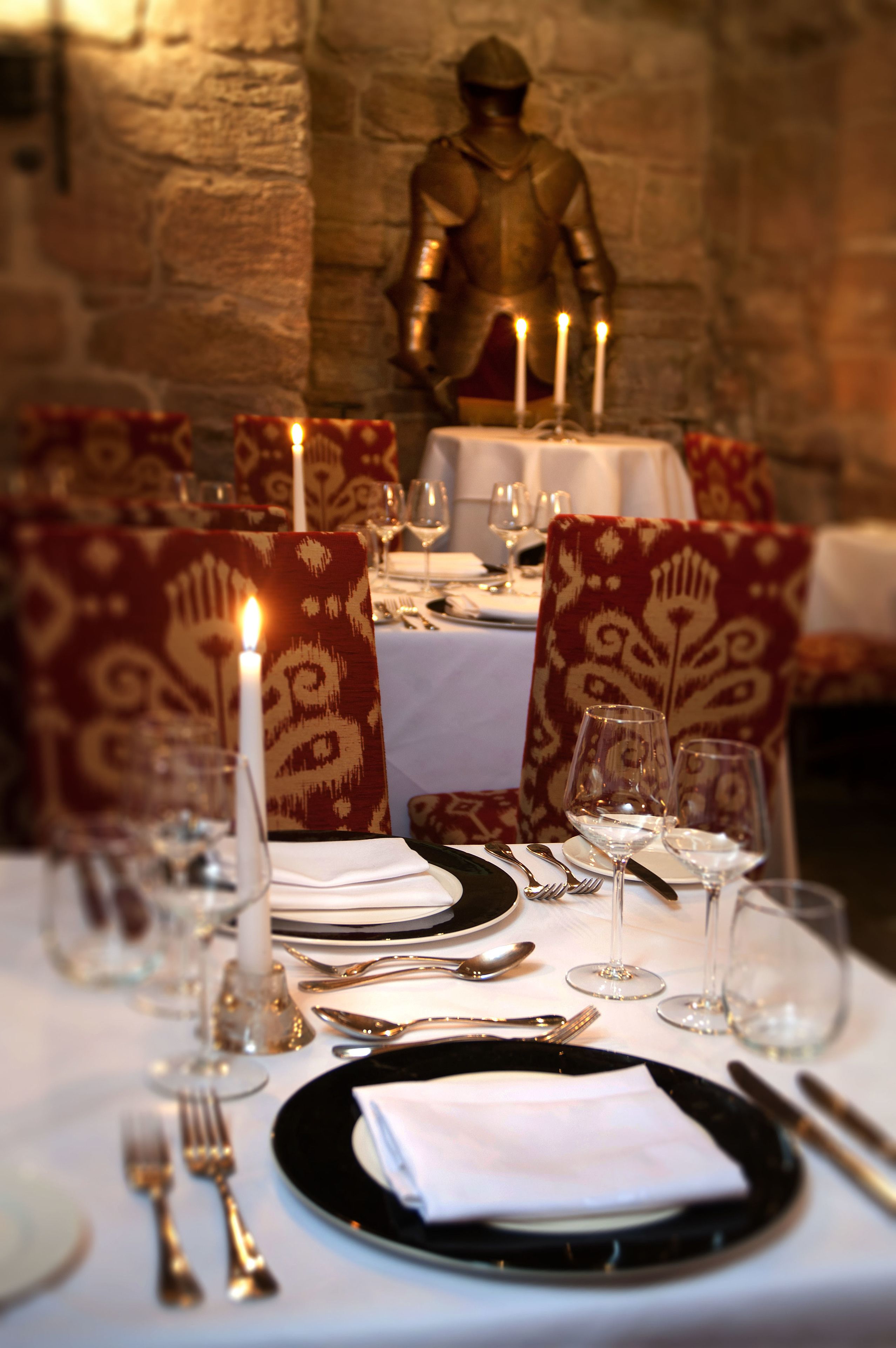 A dining table set with a candle, plates, cutlery, and glasses.