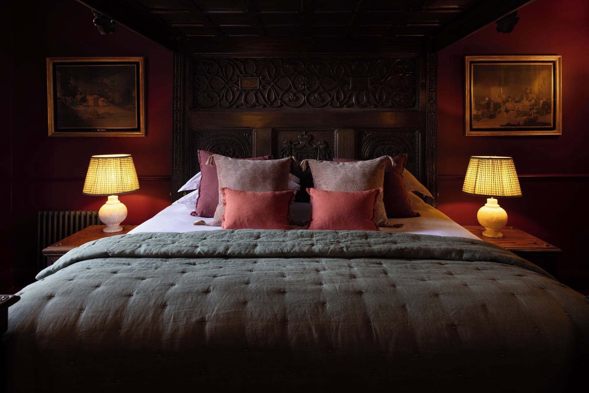 A bedroom with a large bed, two nightstands with lamps, and a decorative headboard.