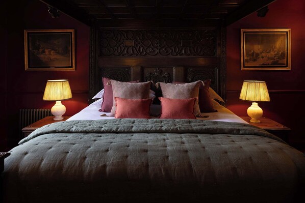 Un dormitorio con una cama grande, dos mesitas de noche con lámparas y un cabecero decorativo.
