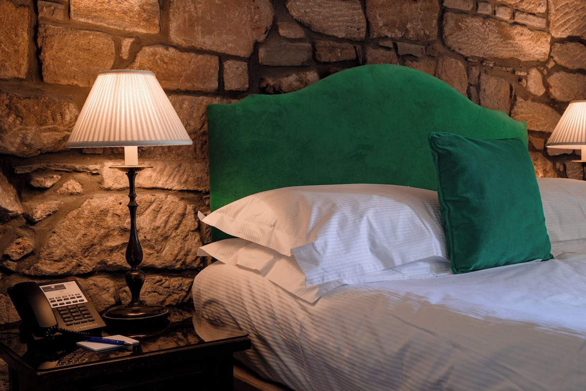 A bed with white linens, a green headboard, and two bedside lamps.